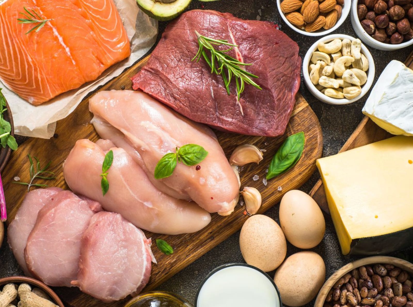 Salmon, beef, chicken, eggs, cheese, and nuts on a wooden board
